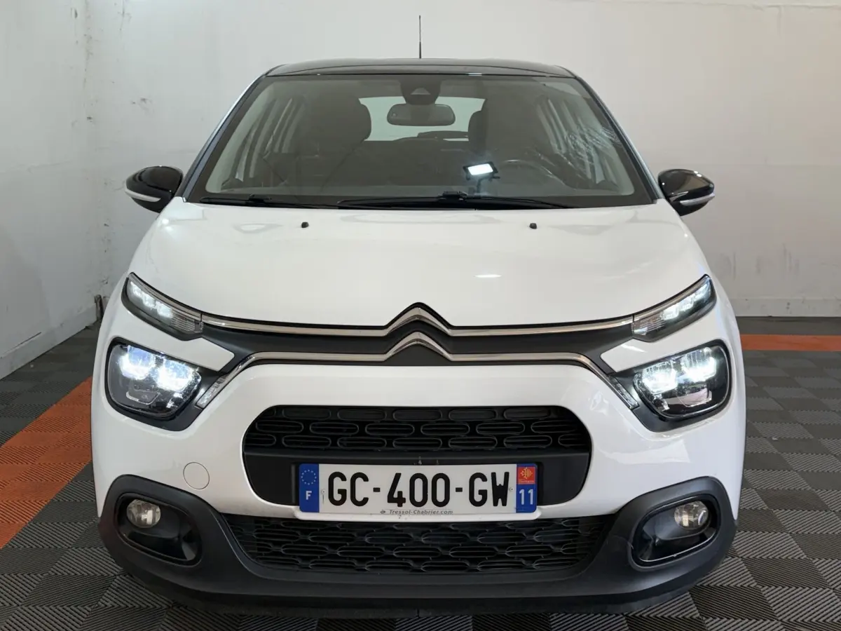 Vue frontale d'une Citroën C3 blanche avec phares LED allumés et calandre noire distinctive.