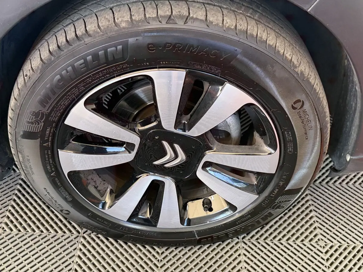 Gros plan sur la roue avant droite d'une Citroën C3 blanche, avec jante alliage bicolore et pneu Michelin e-Primacy.
