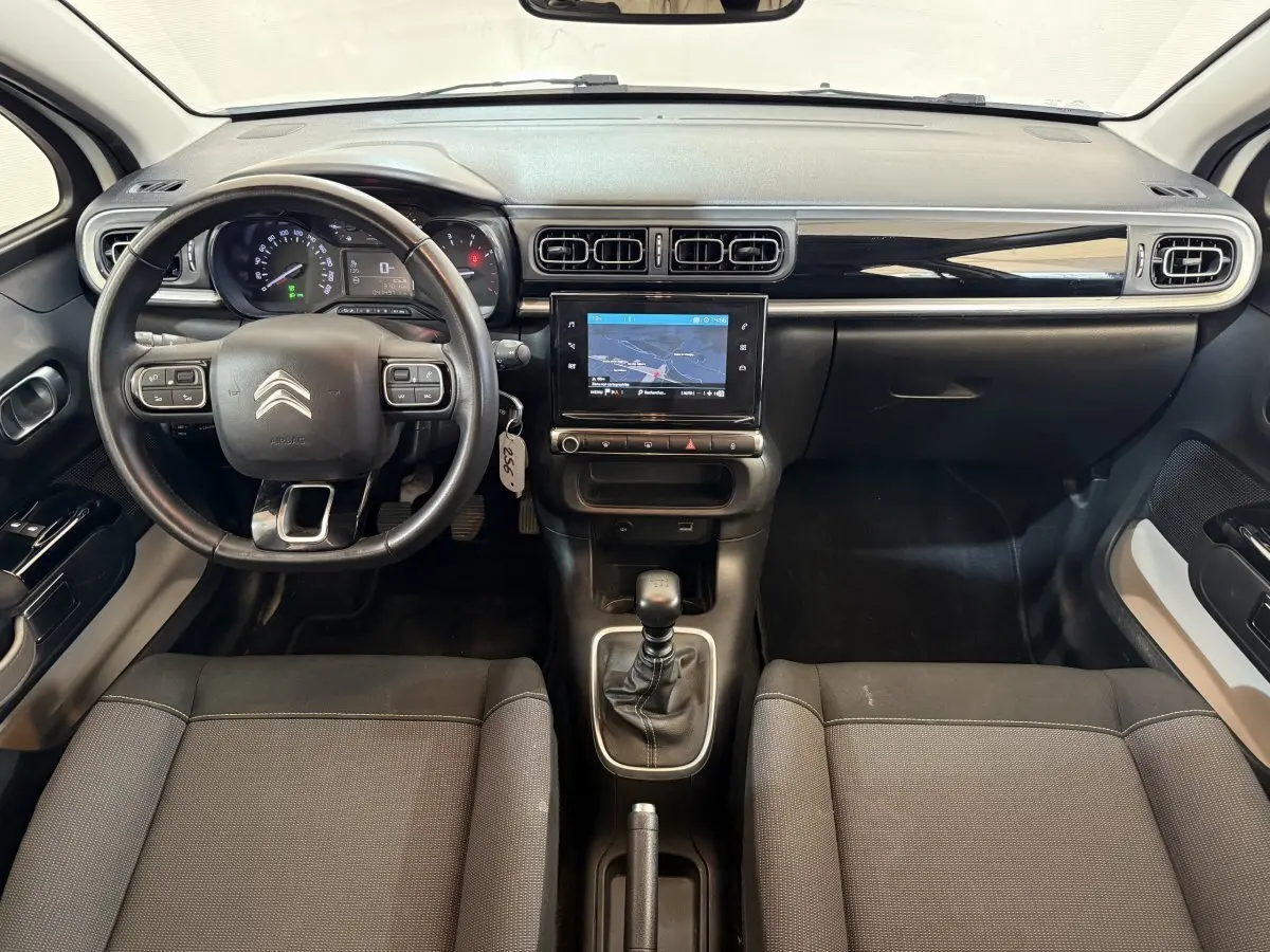 Vue intérieure avant de la Citroën C3 blanche 2021, tableau de bord noir avec écran tactile et volant cuir multifonctions.