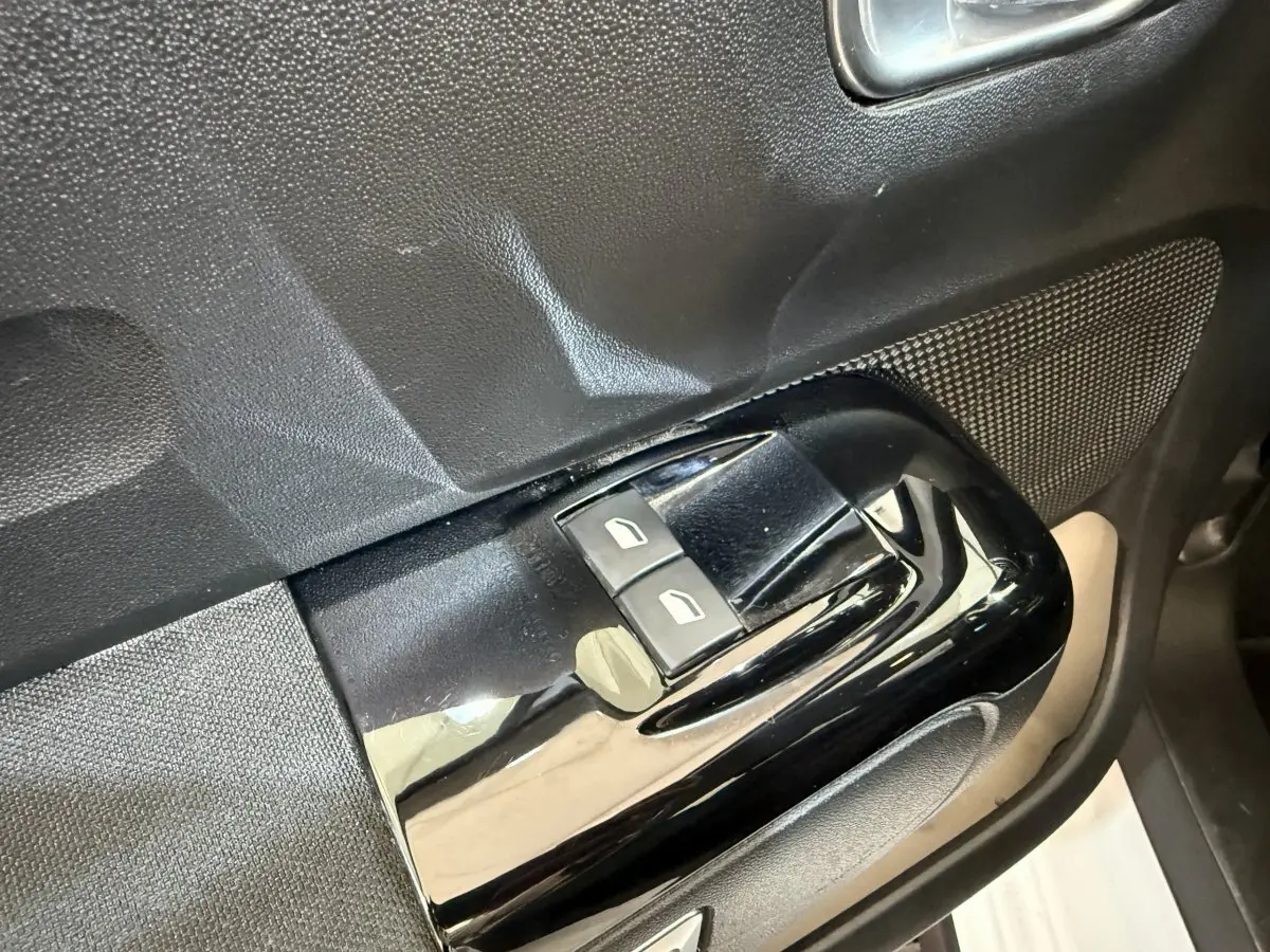 Gros plan sur les commandes de lève-vitres avant gauche d’une Citroën C3 blanche, finition Shine Business.