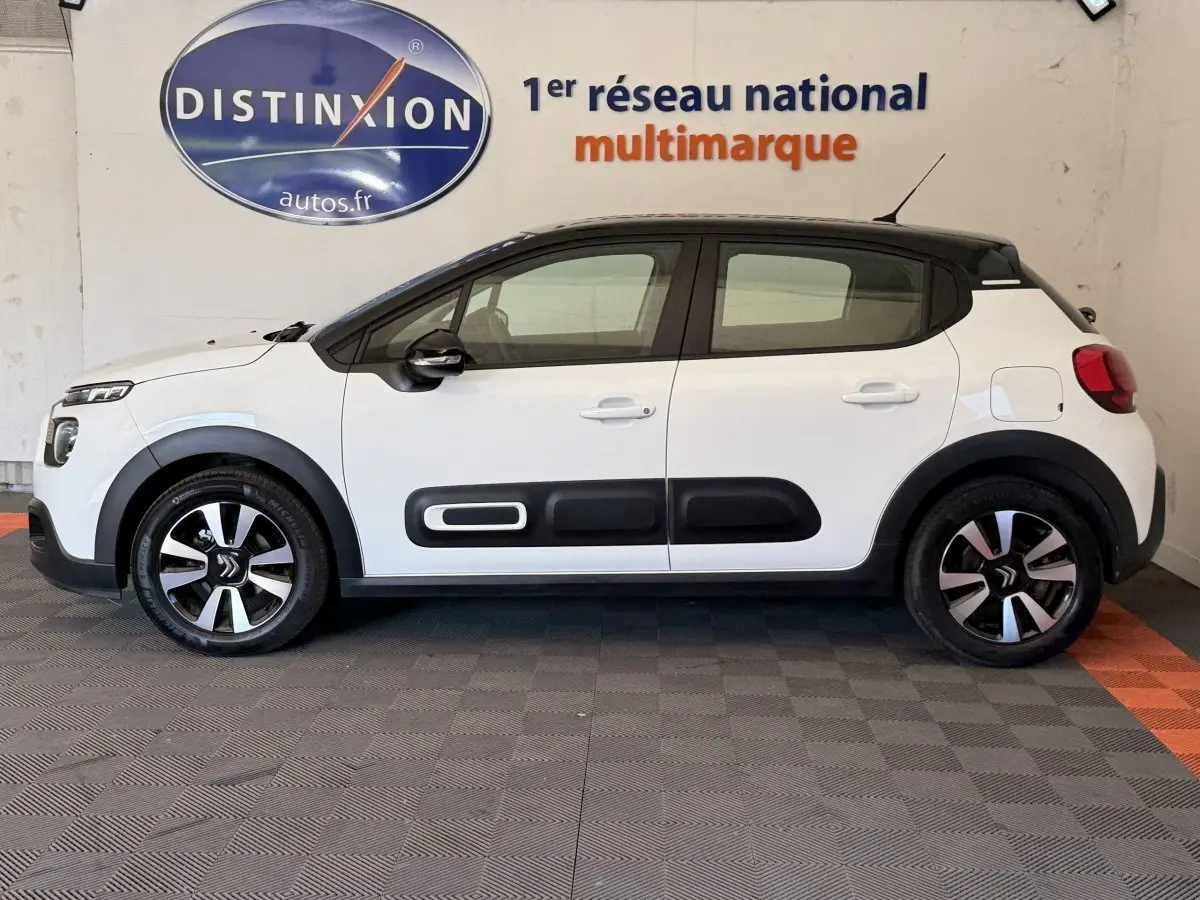 Vue de profil côté gauche d'une Citroën C3 blanche 2021 avec protections noires sur les portières et jantes bicolores.