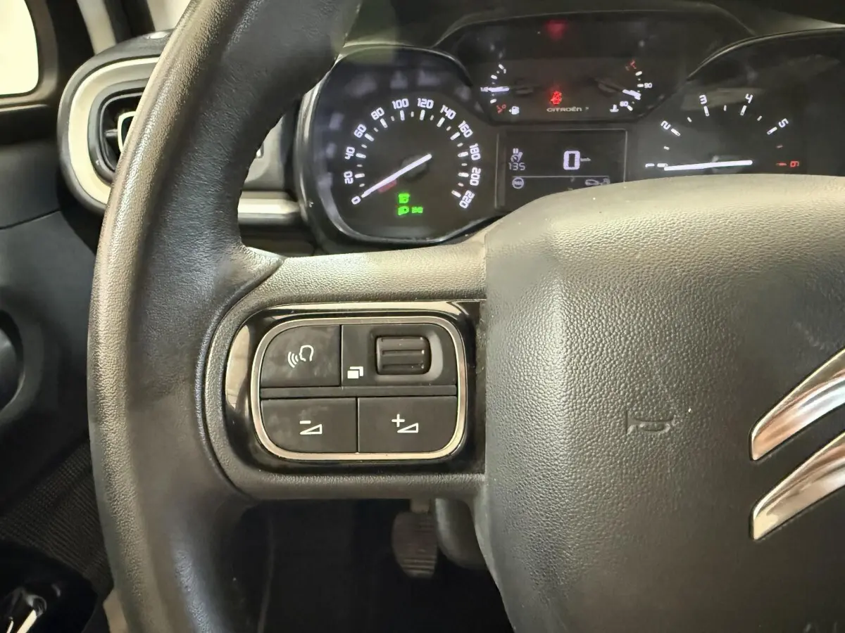 Gros plan sur le volant noir de la Citroën C3 2021 avec commandes intégrées et tableau de bord éclairé en arrière-plan.