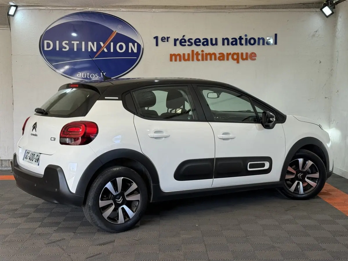 Vue de profil côté droit d'une Citroën C3 blanche avec toit noir et protections latérales noires distinctives.
