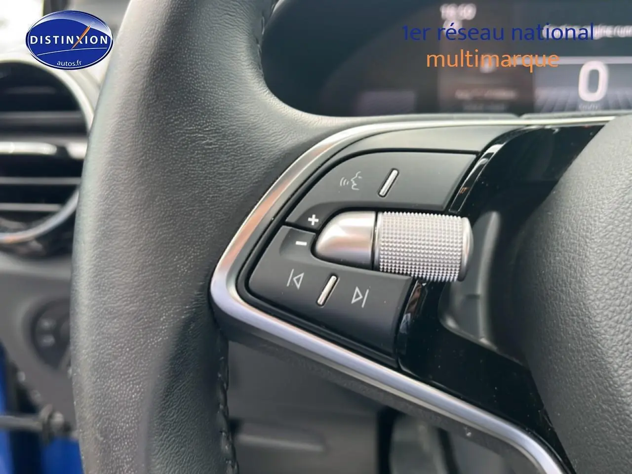 Gros plan sur les commandes du volant cuir noir de la Skoda Fabia bleu, mettant en valeur la molette argentée et les boutons multifonctions.