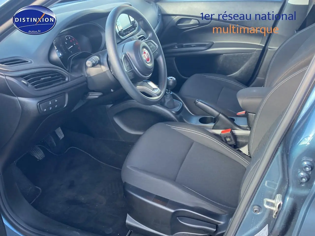 Vue intérieure côté conducteur de la Fiat Tipo 1.6 Multijet bleu, volant multifonction et boîte manuelle visibles.