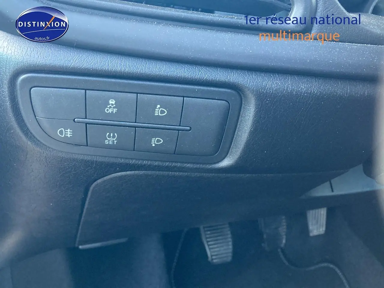 Gros plan sur les commandes d'éclairage et de sécurité sous le tableau de bord d'une FIAT TIPO bleu 2024.