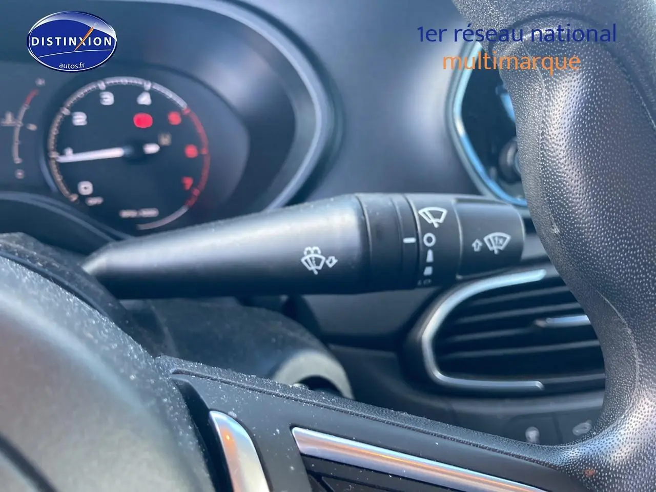 Gros plan sur la commande d’essuie-glace à gauche du volant dans l’habitacle d’une Fiat Tipo bleu 2024.