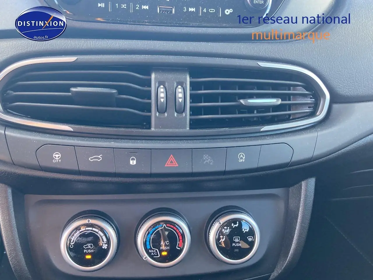 Vue rapprochée de la console centrale noire du Fiat Tipo 1.6 Multijet 130, avec commandes clim manuelle et aérateurs.