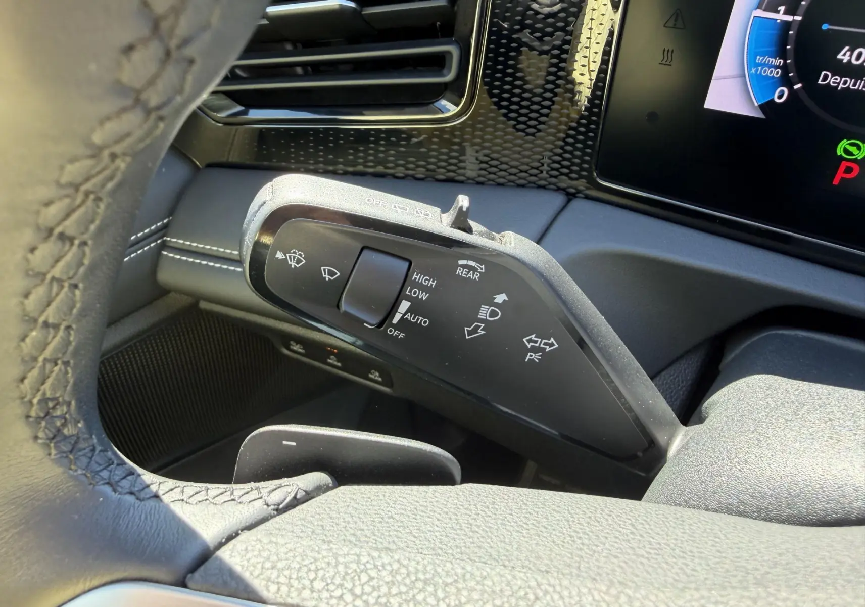 Gros plan sur la commande des essuie-glaces et clignotants du Volkswagen Tiguan 2025, intérieur noir avec coutures blanches.