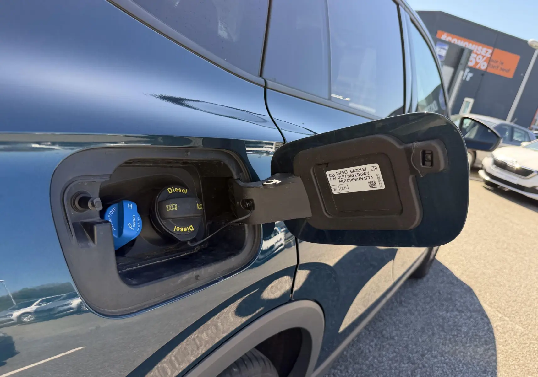 Vue rapprochée du côté gauche arrière du Volkswagen Tiguan bleu 2025 montrant la trappe à carburant diesel ouverte.