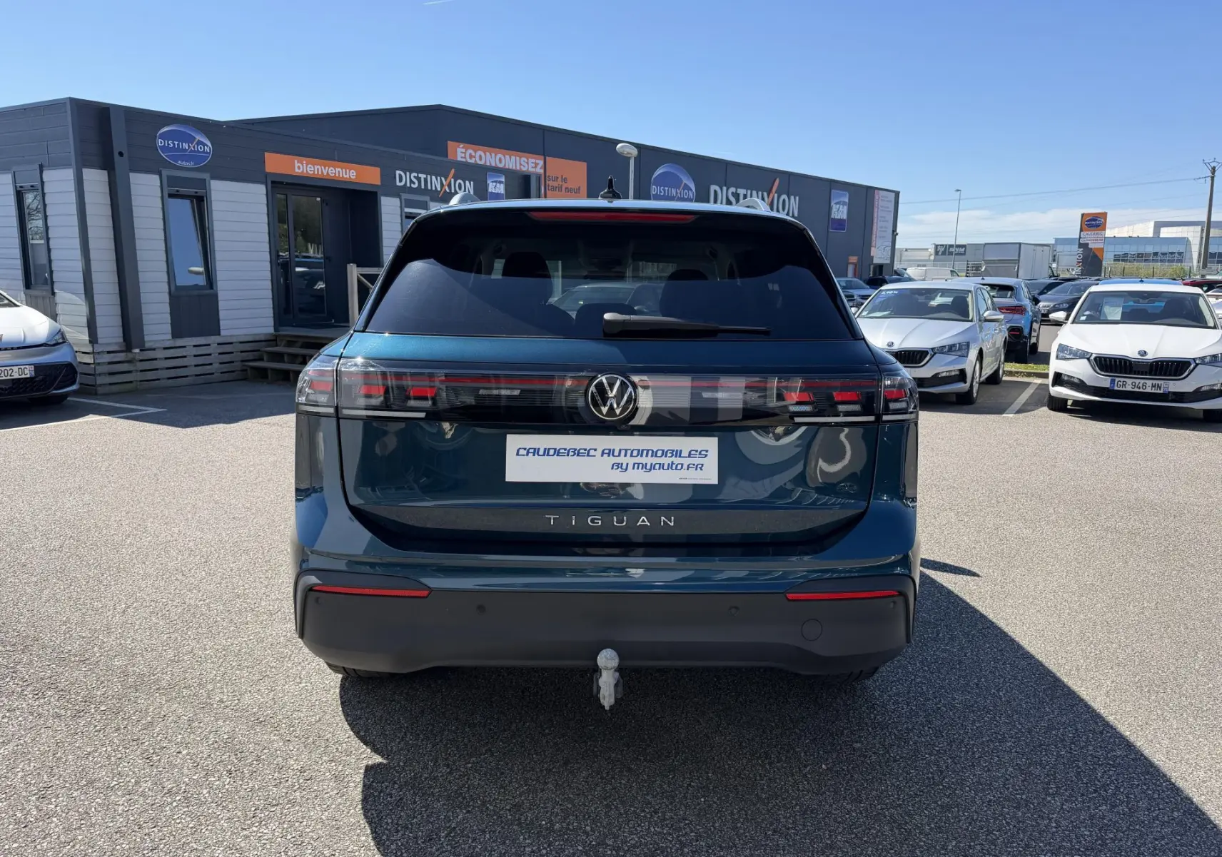 Vue arrière d'un Volkswagen Tiguan bleu 2025 avec crochet d'attelage escamotable sur parking extérieur.