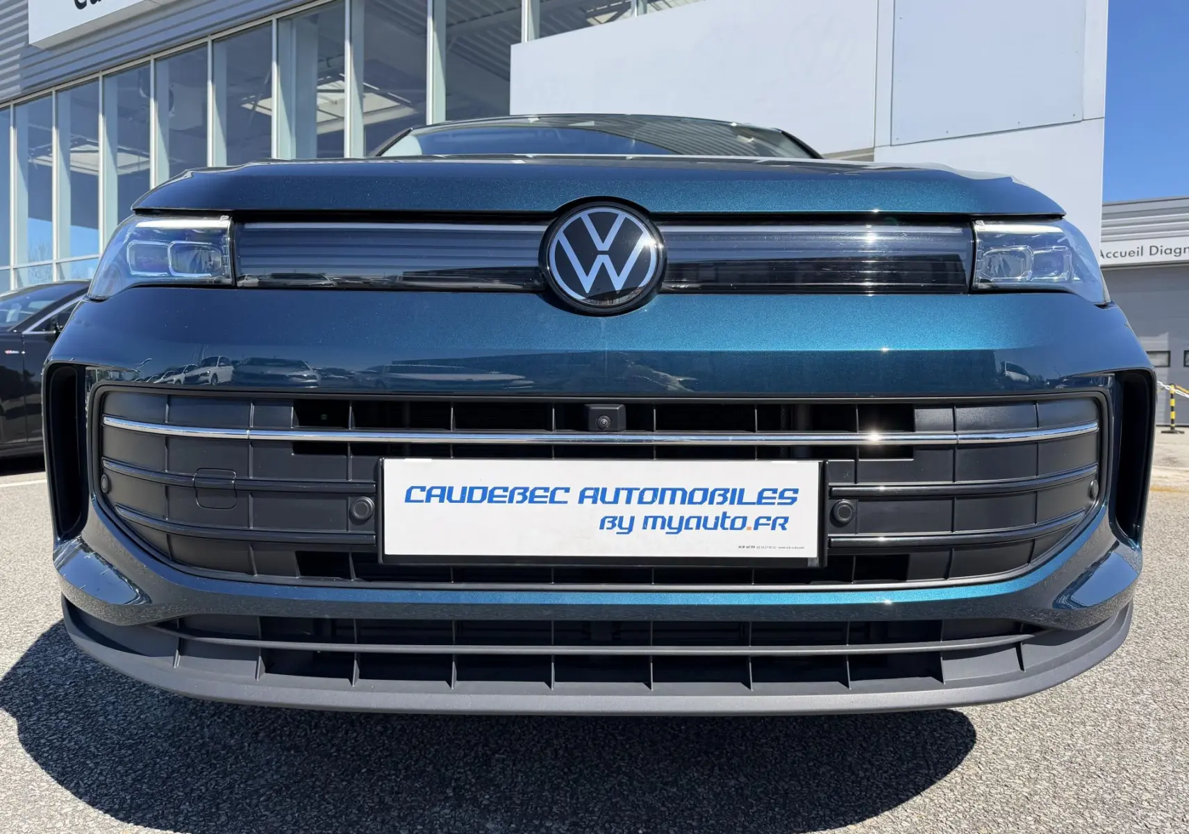 Vue frontale rapprochée du Volkswagen Tiguan bleu 2025 avec calandre noire et logo VW central lumineux.