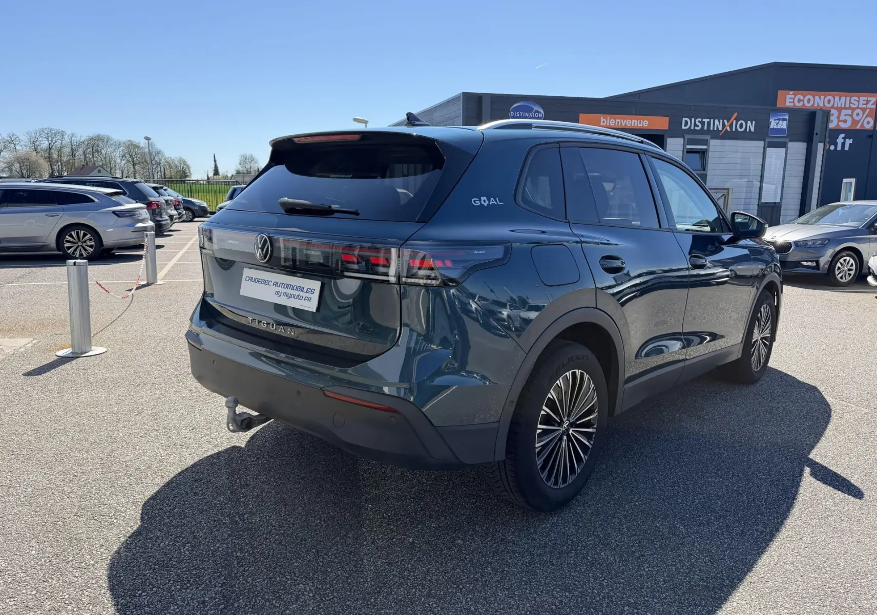 Vue 3/4 arrière droite du Volkswagen Tiguan bleu 2025 avec crochet d'attelage escamotable et jantes alliage 18 pouces.