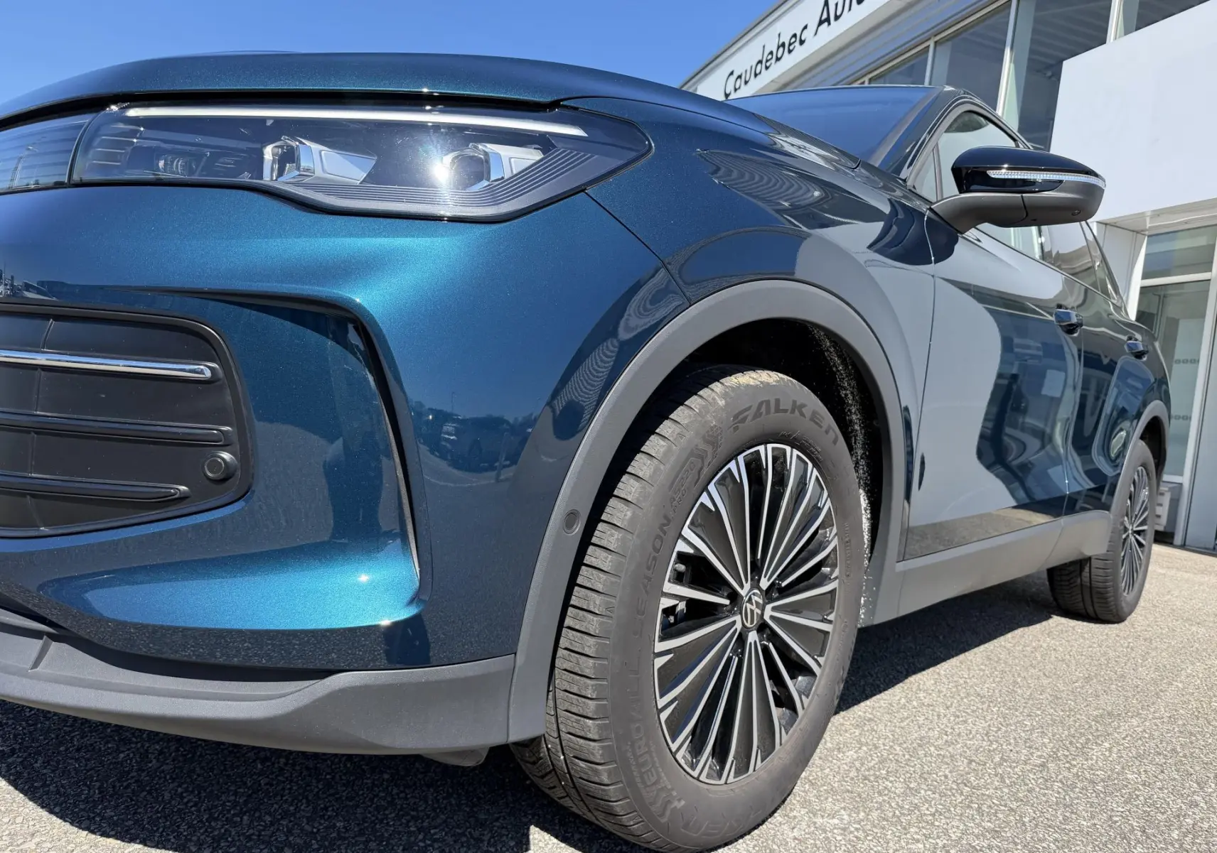 Vue en gros plan 3/4 avant droit du Volkswagen Tiguan bleu métallisé, mettant en valeur le projecteur LED et la jante alliage 18 pouces.