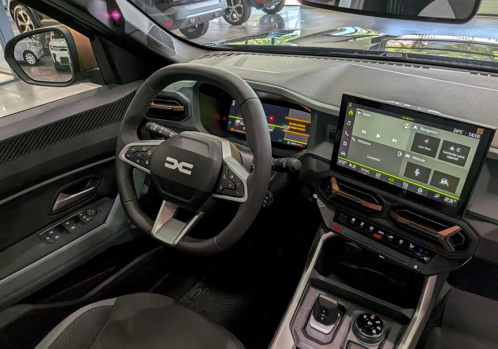 Vue intérieure côté conducteur du Dacia Bigster Hybrid-G 150 4x4, avec tableau de bord numérique et écran tactile central.