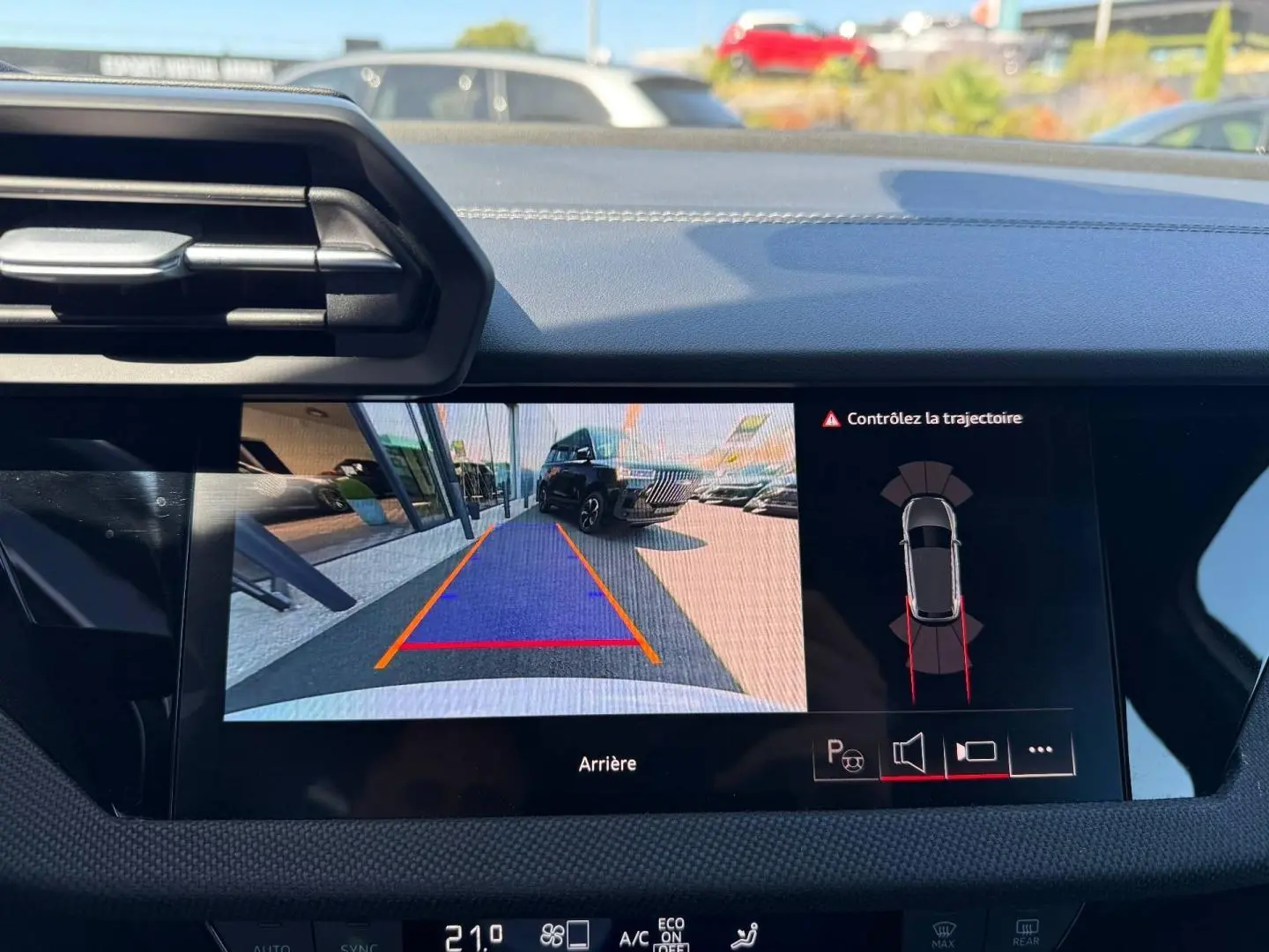 Écran central montrant la caméra de recul avec vue arrière d’un véhicule noir en stationnement, intérieur Audi A3 blanc.