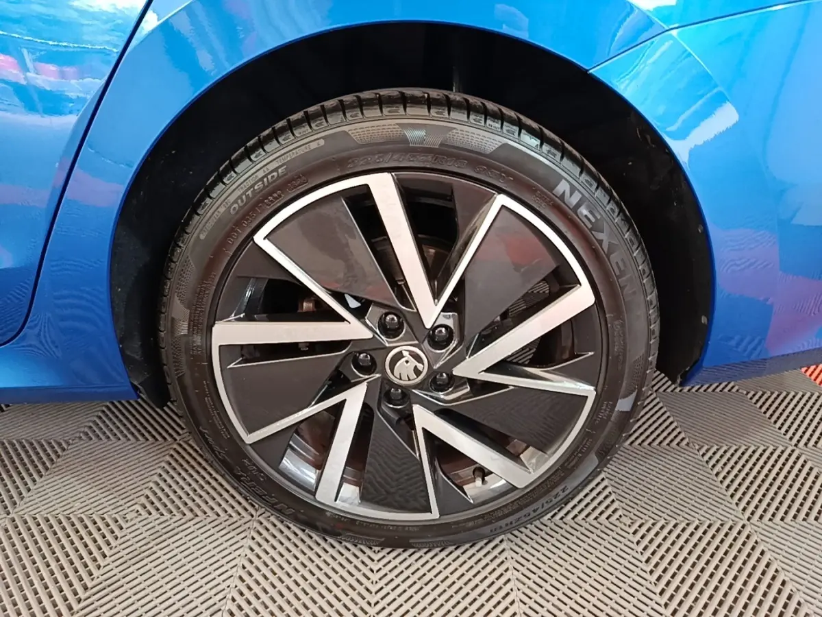 Gros plan sur la roue arrière droite d’une Skoda Octavia bleue 2022 avec jante alliage noire et argentée au design moderne.