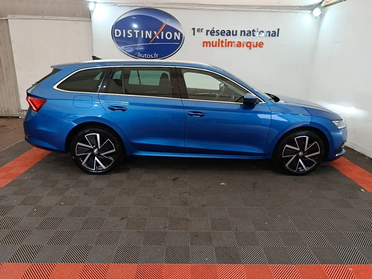 Vue latérale droite d'une Skoda Octavia break bleu 2022 avec jantes noires et détails chromés sur les vitres.