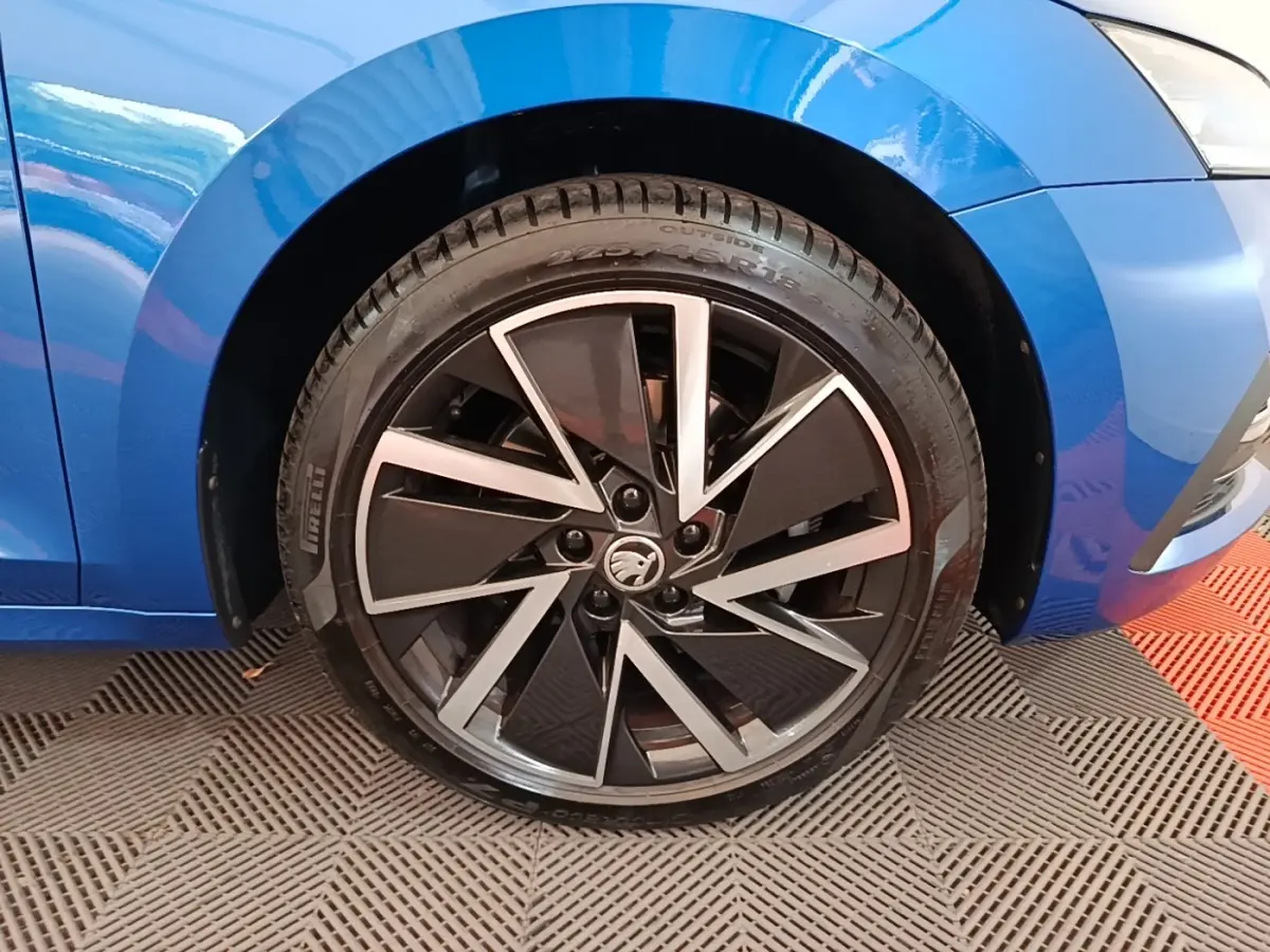 Gros plan sur la roue avant droite d'une Skoda Octavia bleu électrique avec jante alliage noire et argentée.