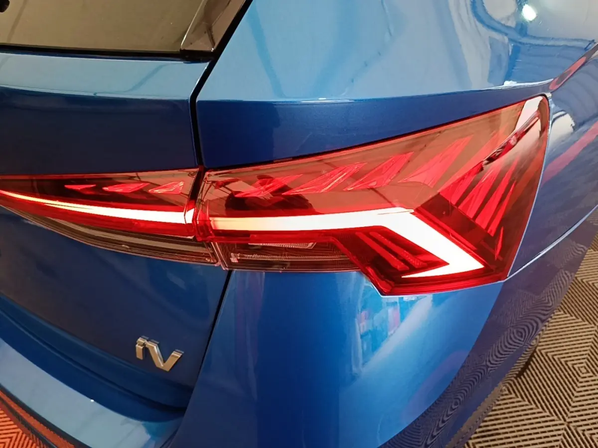 Gros plan sur le feu arrière droit rouge d’une Skoda Octavia hybride rechargeable bleue, avec logo iV visible.