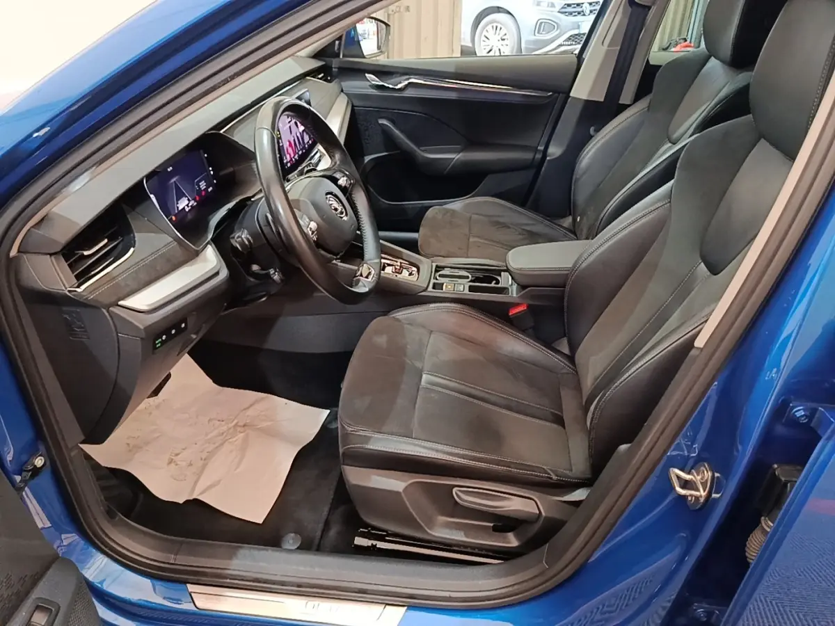 Vue intérieure côté conducteur de la Skoda Octavia bleue 2022, avec sièges noirs et tableau de bord numérique.