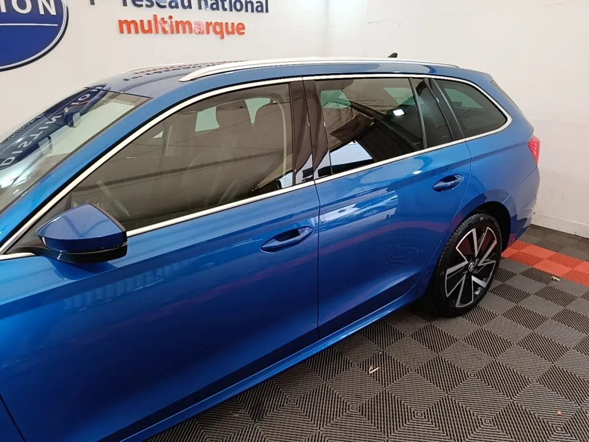 Vue latérale côté gauche d'une Skoda Octavia break bleu électrique, avec jantes alliage et rétroviseur assorti.