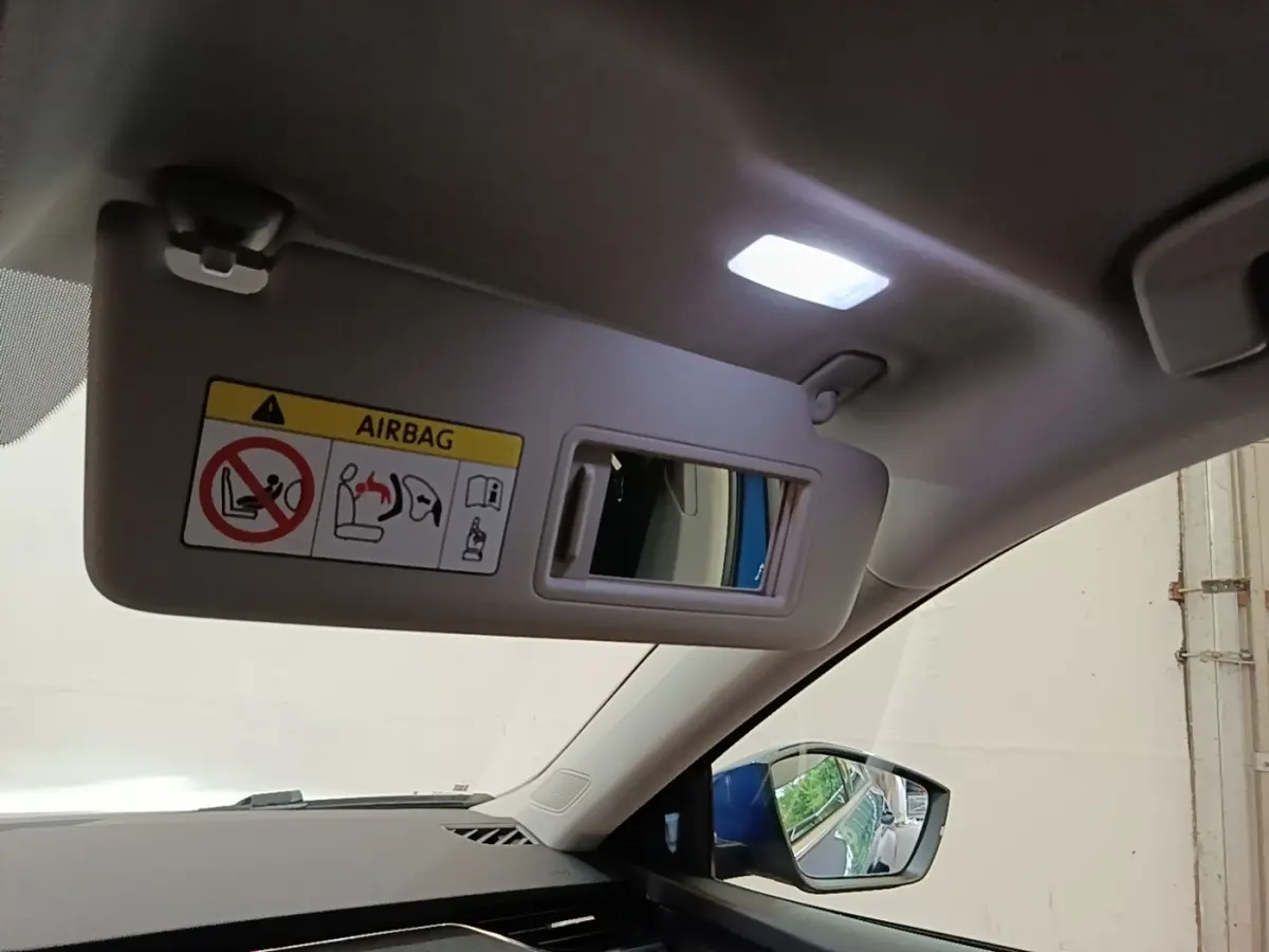 Détail intérieur du pare-soleil côté conducteur avec miroir et rétroviseur extérieur bleu visible sur Skoda Octavia 2022.