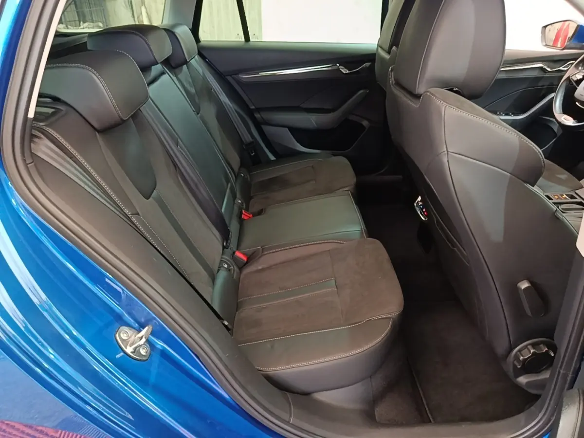 Vue intérieure côté arrière gauche de la Skoda Octavia bleue, montrant la banquette arrière en cuir et alcantara noir.