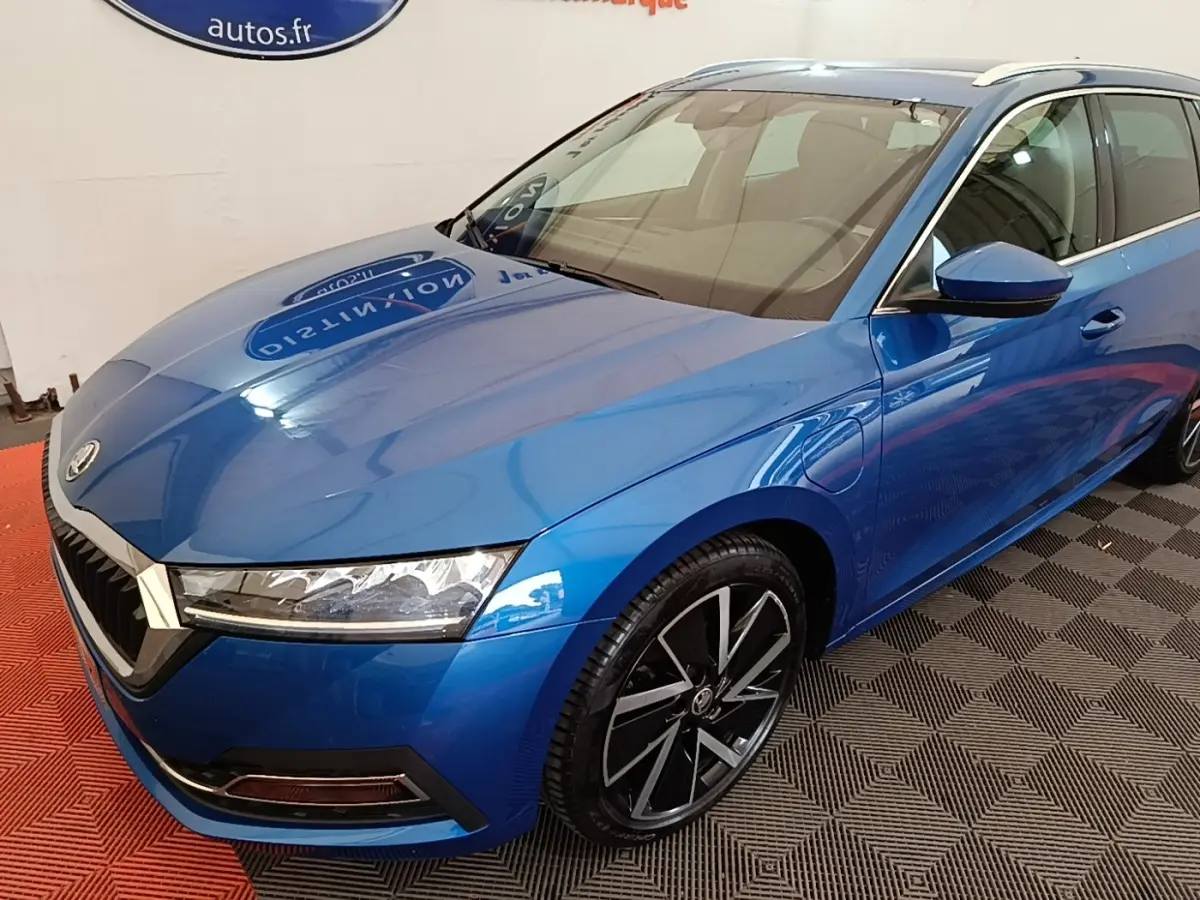 Vue 3/4 avant droite d'une Skoda Octavia bleu électrique avec jantes alliage noires et prises de recharge latérales visibles.