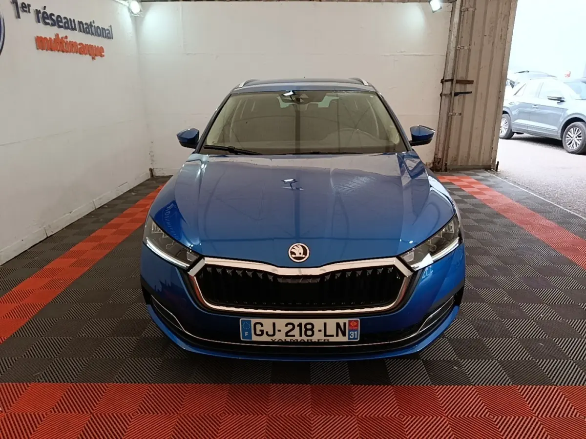 Vue avant d'une Skoda Octavia bleu électrique garée en intérieur, mettant en valeur sa calandre chromée et ses phares LED.