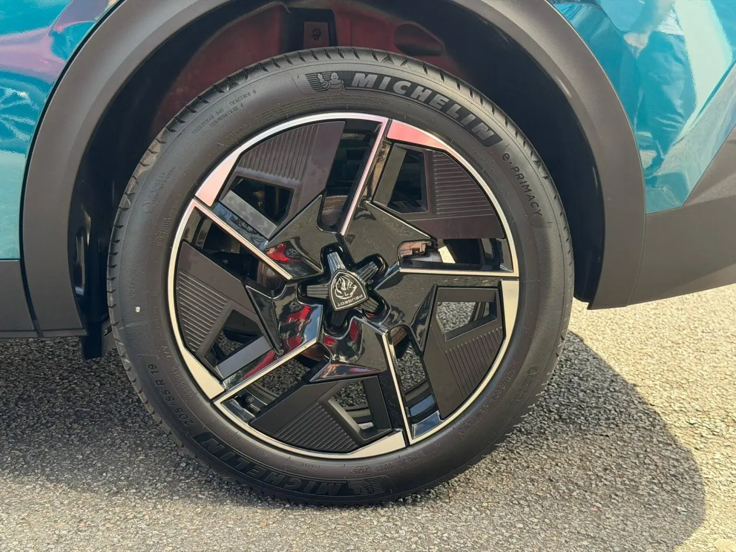 Gros plan sur la roue avant gauche avec jante alu noire et chromée du Peugeot 408 Bleu Obsession.