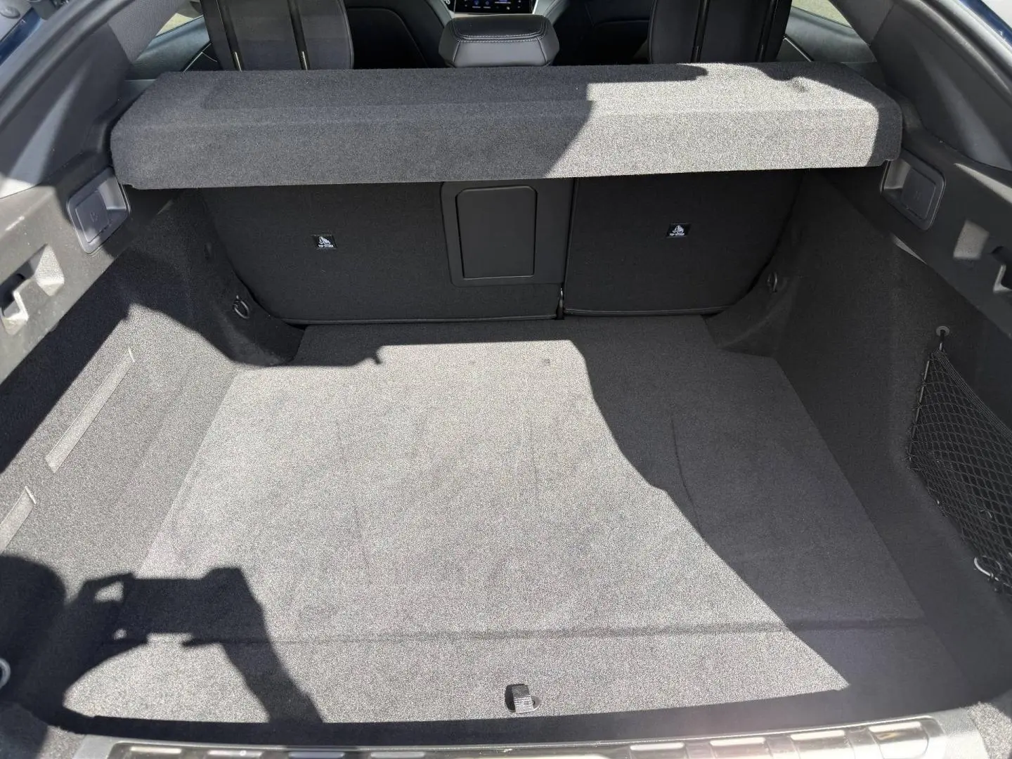 Vue du coffre spacieux de la Peugeot 408 Hybrid 145ch GT, intérieur noir avec cache-bagages relevé.