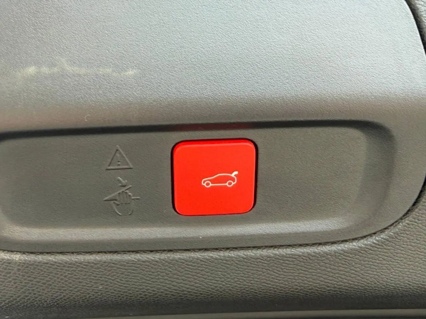 Bouton rouge d'ouverture électrique du coffre sur tableau de bord intérieur d'une Peugeot 408 Bleu Obsession.