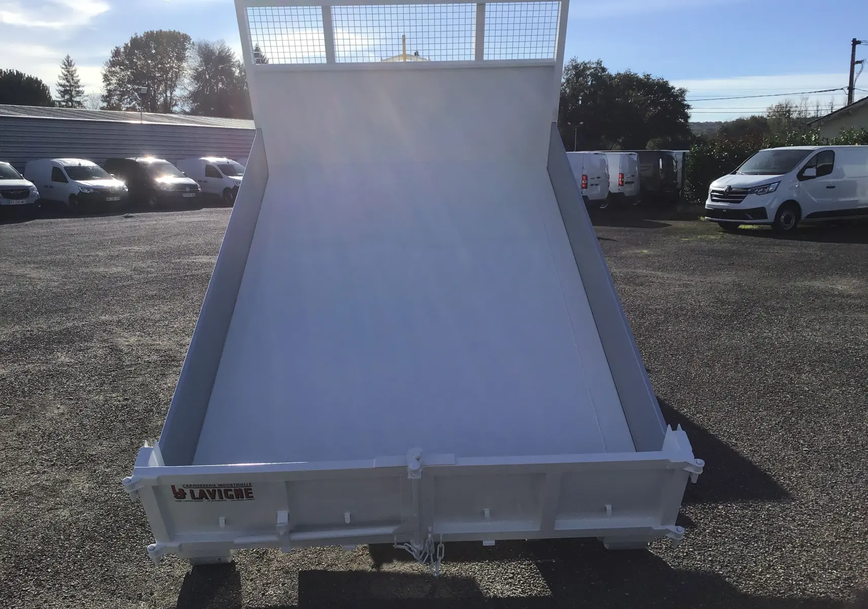 Vue arrière d'une benne blanche relevée sur un Ford Transit Châssis Cabine avec bras Polybenne et grille de protection.