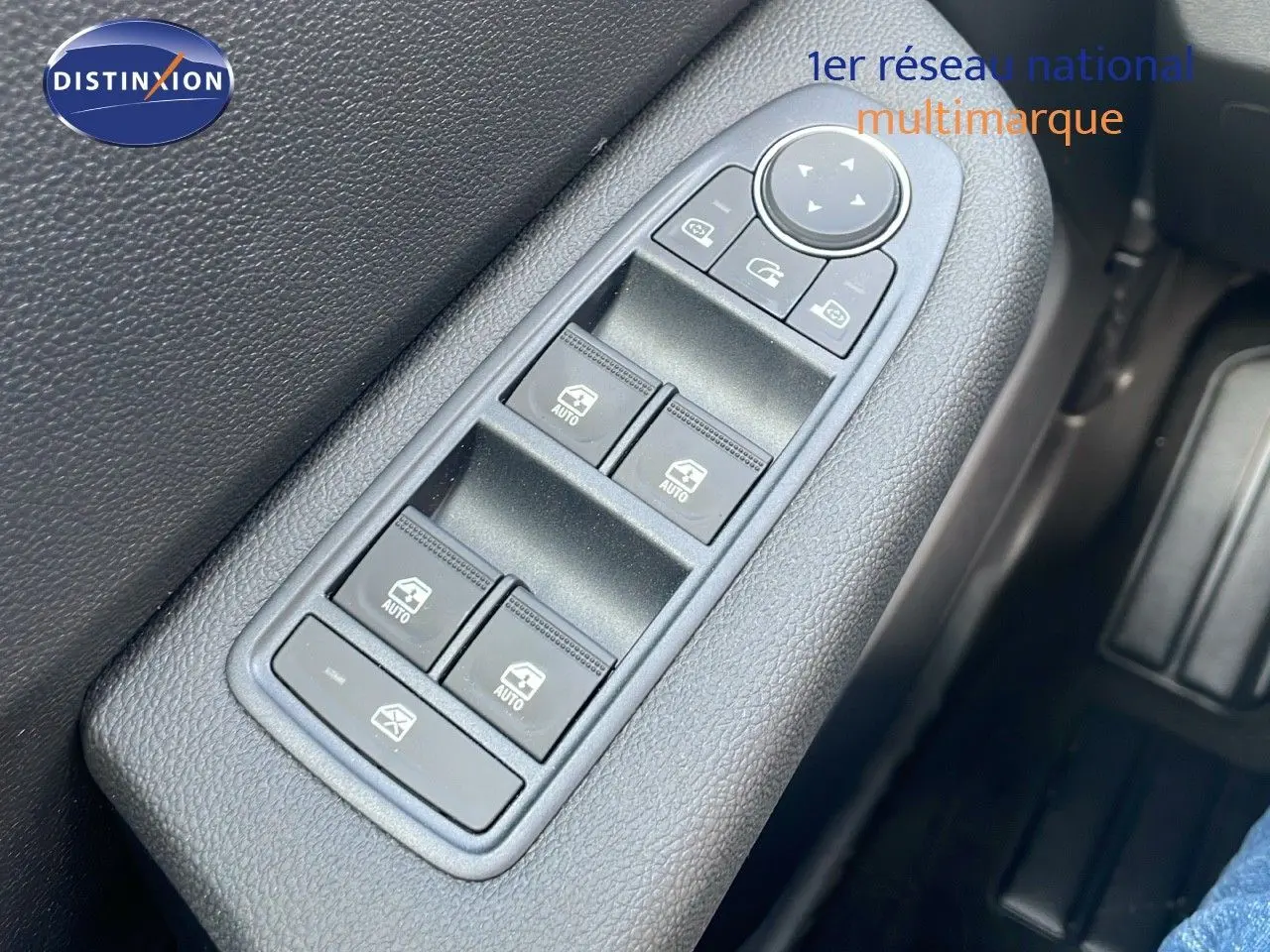 Gros plan sur les commandes des vitres électriques et rétroviseurs côté gauche d'une Renault Clio gris schiste métal 2025.