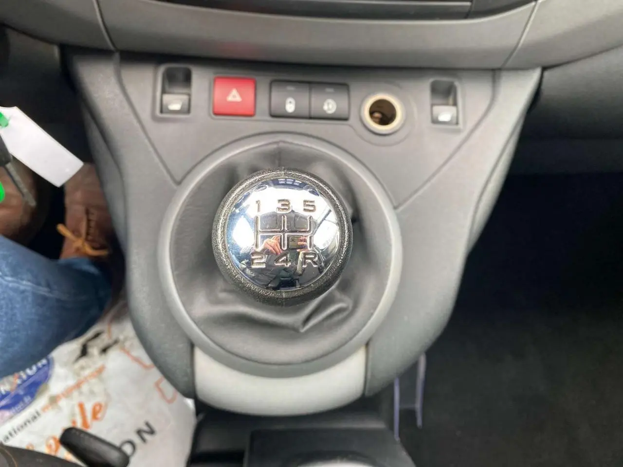 Gros plan sur le levier de vitesse manuel du Peugeot Partner gris Artense, avec tableau de bord et commandes visibles.