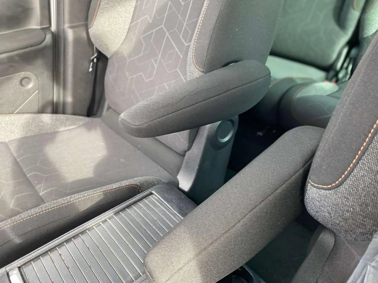 Gros plan sur les sièges avant gris foncé du Peugeot Partner 2017 avec accoudoirs et surpiqûres orange visibles.