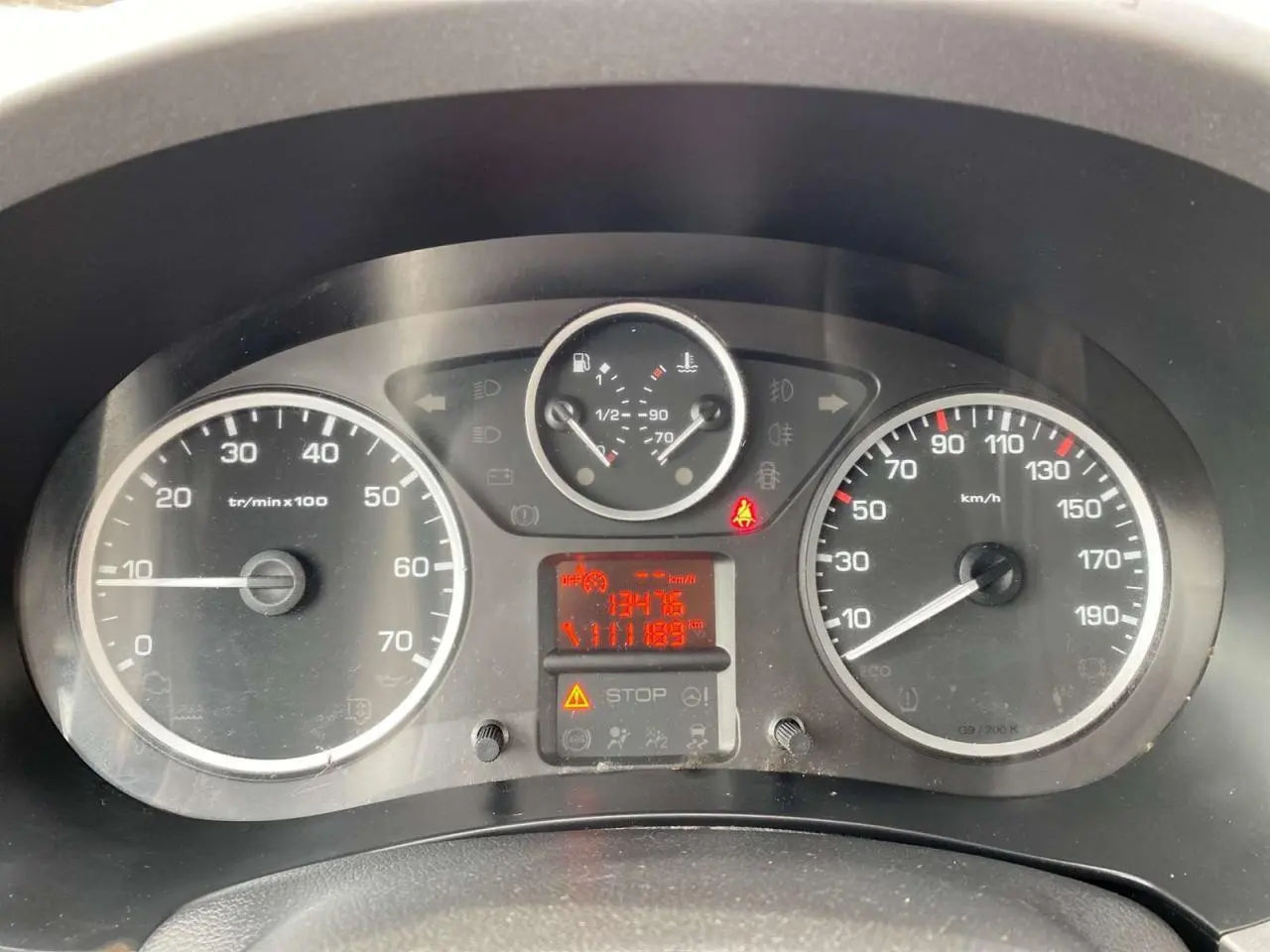 Vue rapprochée du tableau de bord du Peugeot Partner gris Artense 2017, affichant compteurs et témoins lumineux.