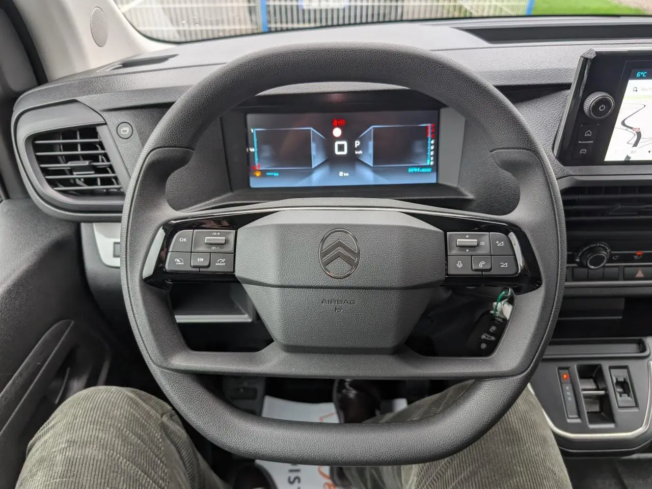 Vue rapprochée du volant noir de la Citroën Jumpy 2025 avec commandes intégrées et tableau de bord numérique.