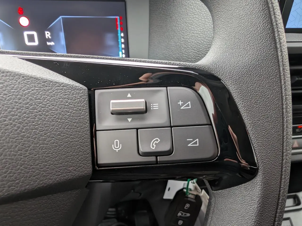 Gros plan sur les commandes au volant noir brillant du Citroën Jumpy gris, avec affichage numérique en arrière-plan.