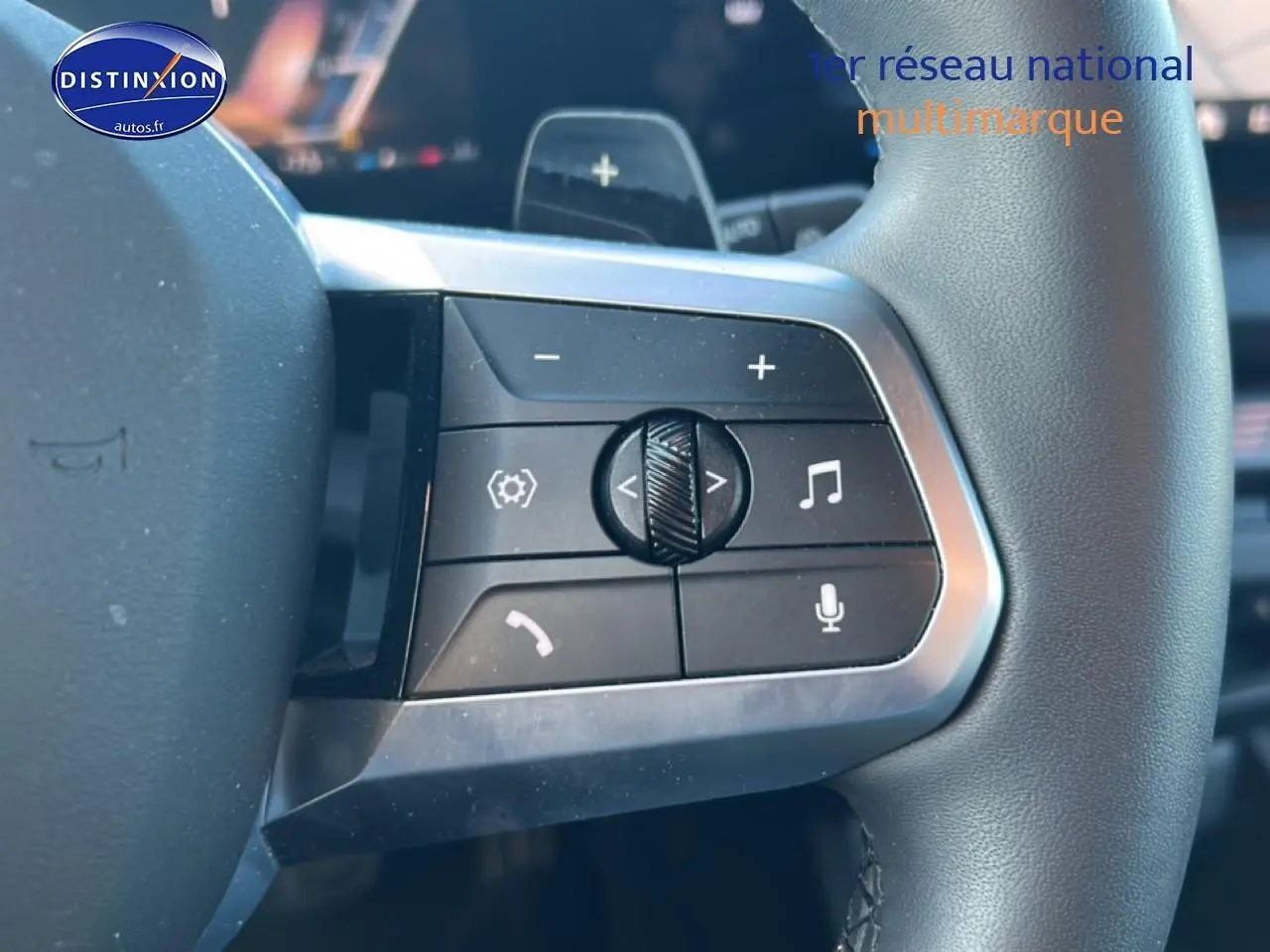 Gros plan sur les commandes gauche du volant de la BMW Série 1 blanche, avec boutons de volume et appels intégrés.