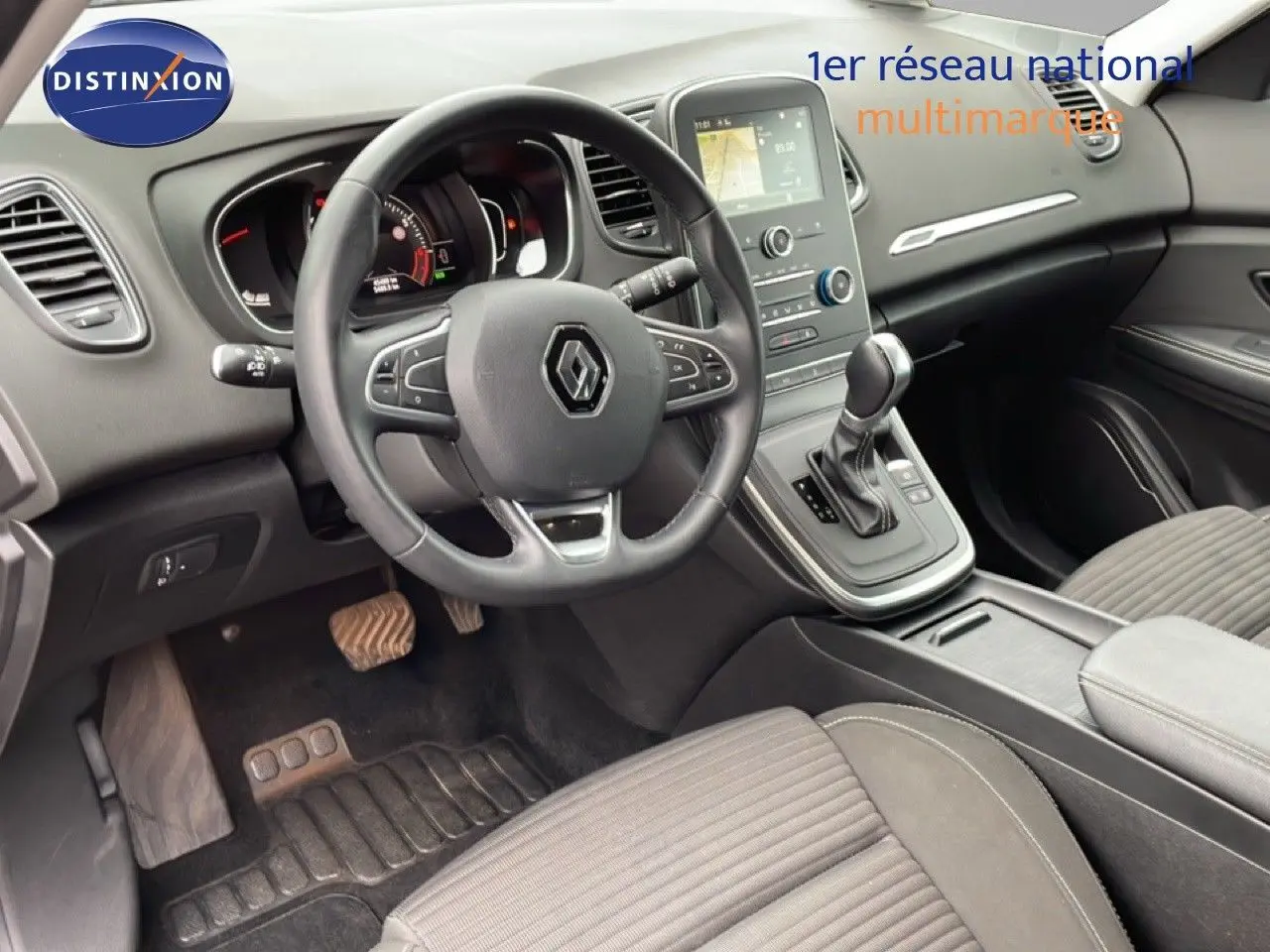 Intérieur noir du Renault Grand Scenic 2022, vue du poste de conduite avec volant multifonction et console centrale.