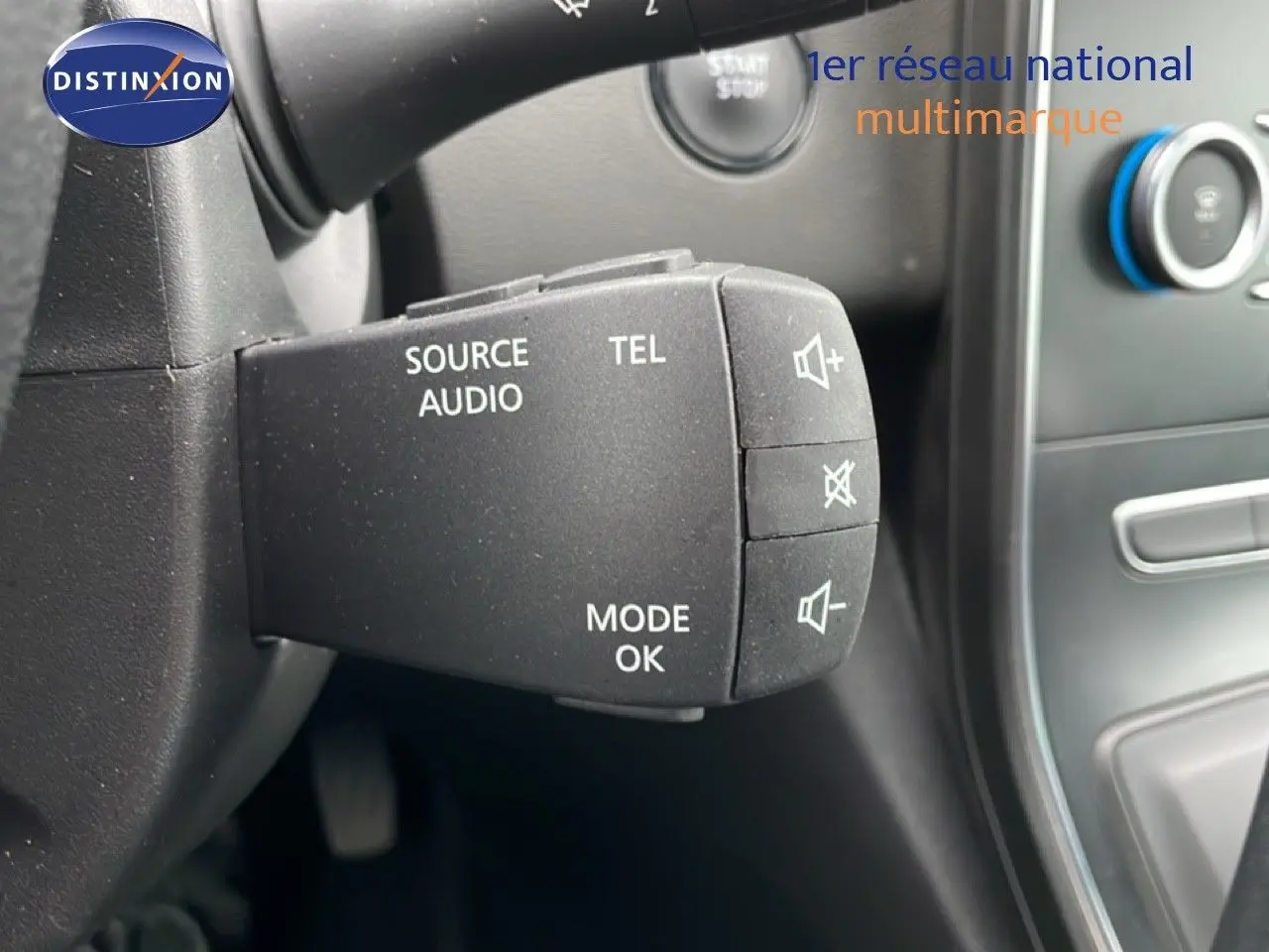 Gros plan sur la commande audio au volant du Renault Grand Scenic noir étoile métal, avec tableau de bord en arrière-plan.