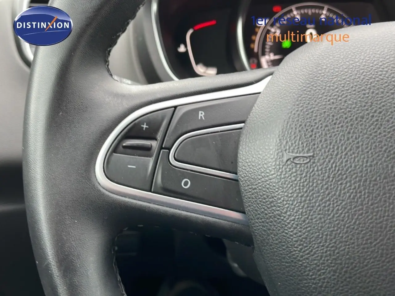 Gros plan sur le volant en cuir noir du Renault Grand Scenic 2022, avec commandes intégrées visibles à gauche.