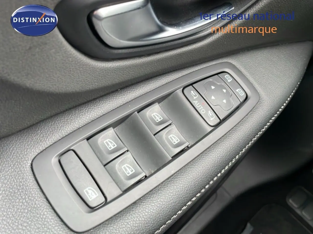 Gros plan sur les commandes de lève-vitres et rétroviseurs côté conducteur d’un Renault Grand Scenic noir étoile métal.