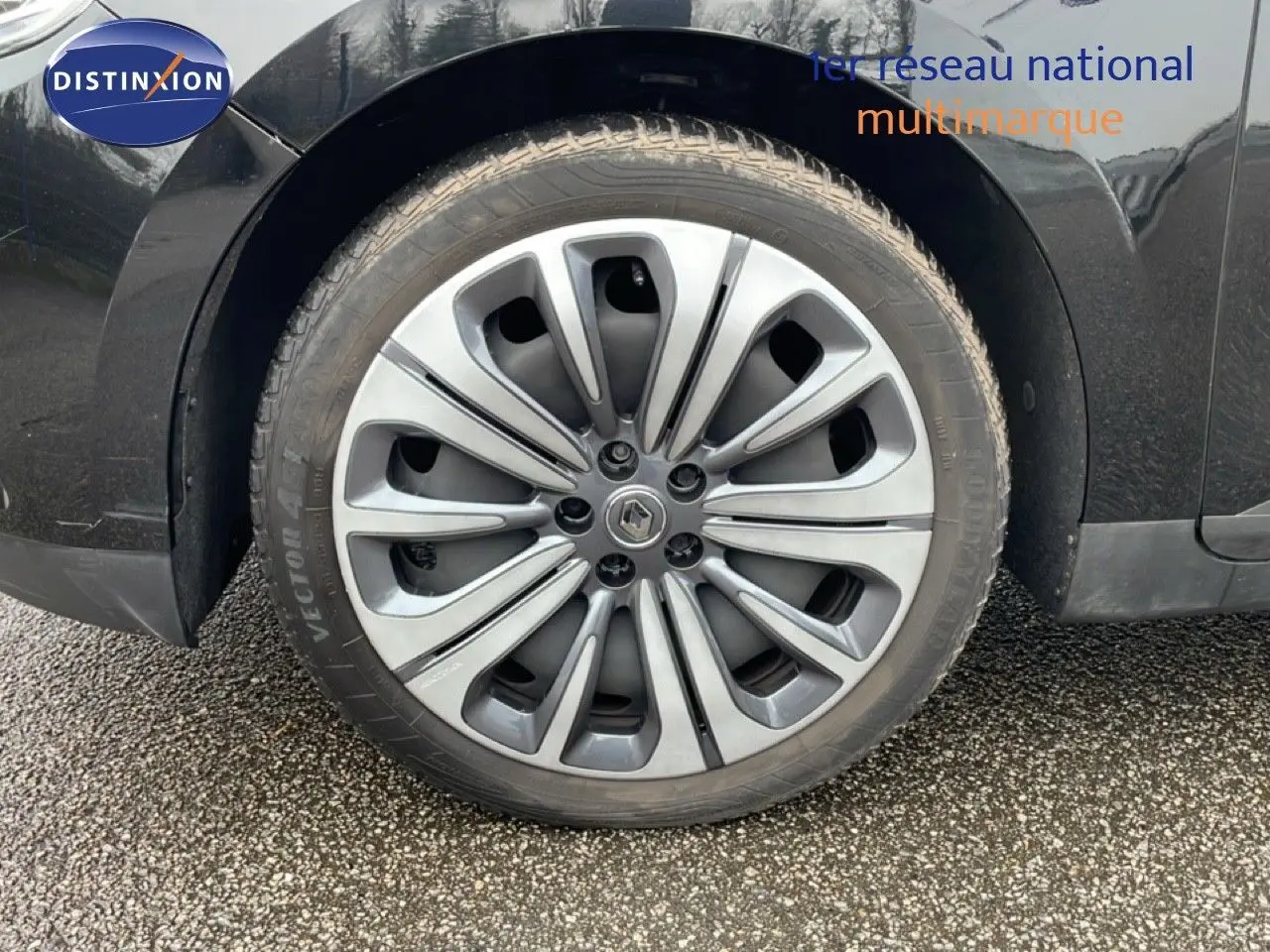 Gros plan sur la roue arrière droite d’un Renault Grand Scénic noir étoile métal avec jante alliage distinctive.