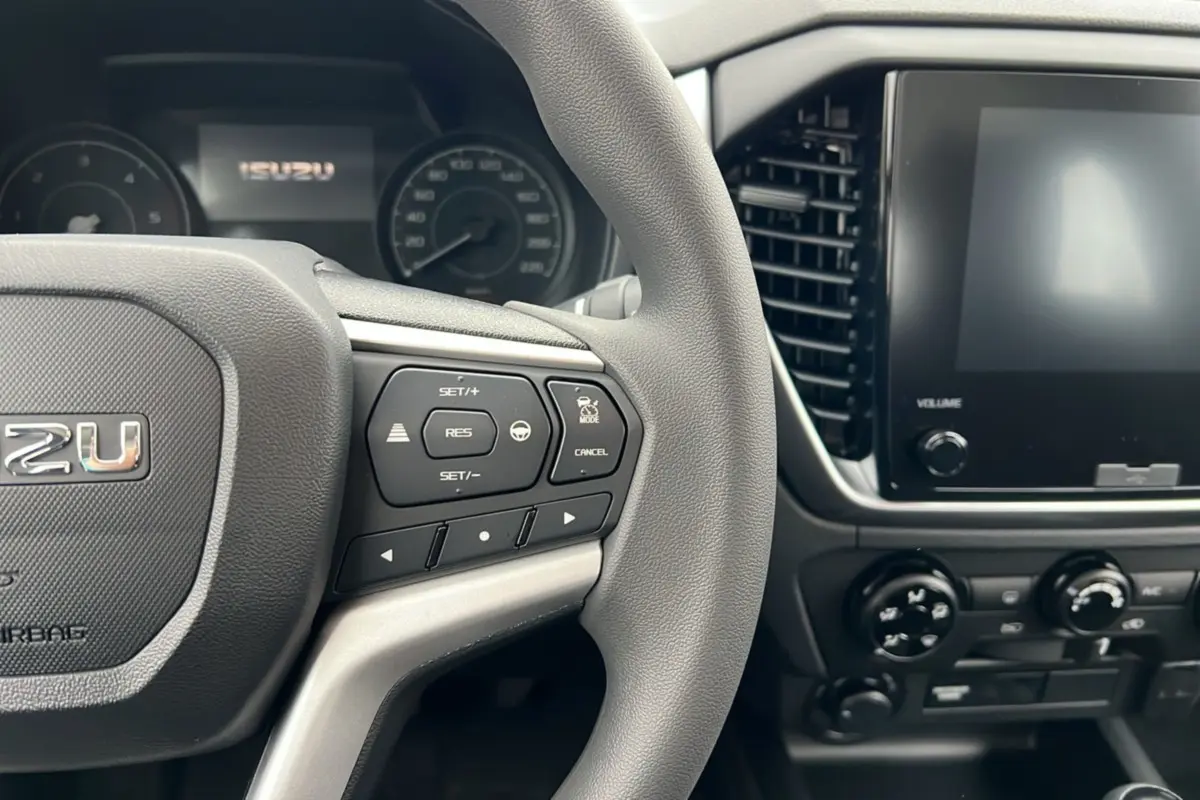 Vue intérieure rapprochée du volant multifonctions et de l’écran tactile du tableau de bord de l’Isuzu D-MAX 2026.