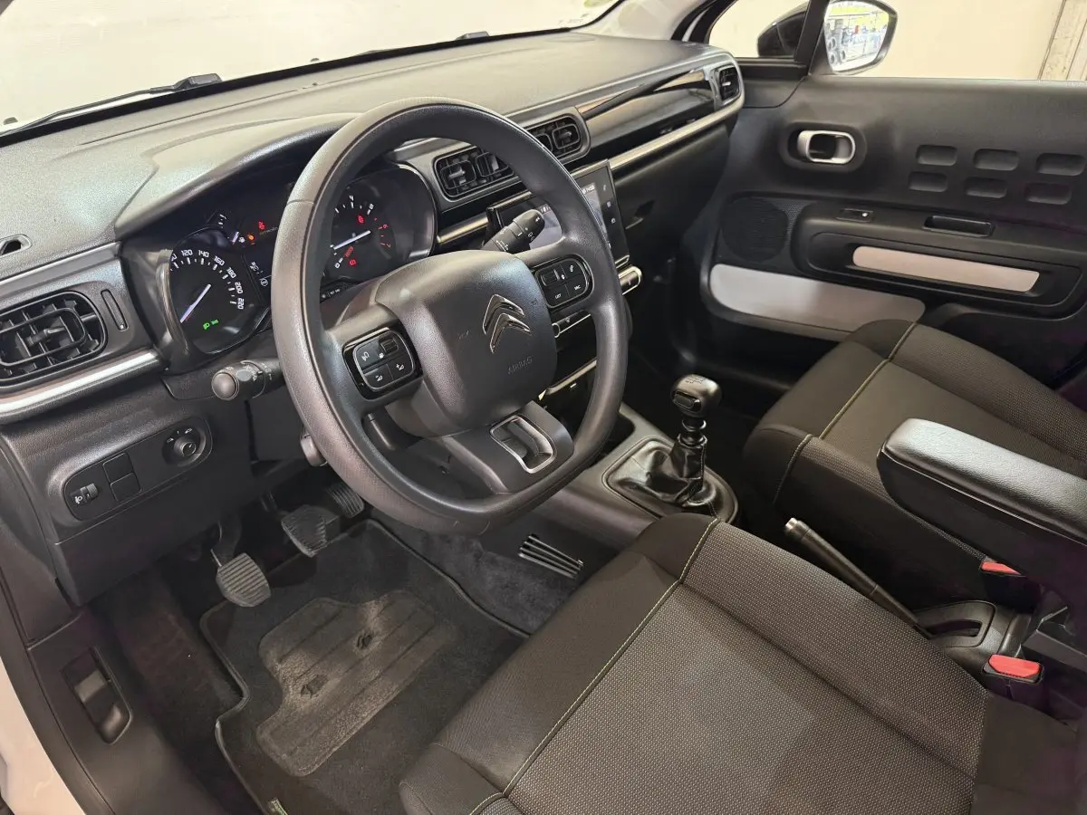 Intérieur avant droit de la Citroën C3 blanche 2021, volant multifonctions, boîte manuelle et tableau de bord moderne.