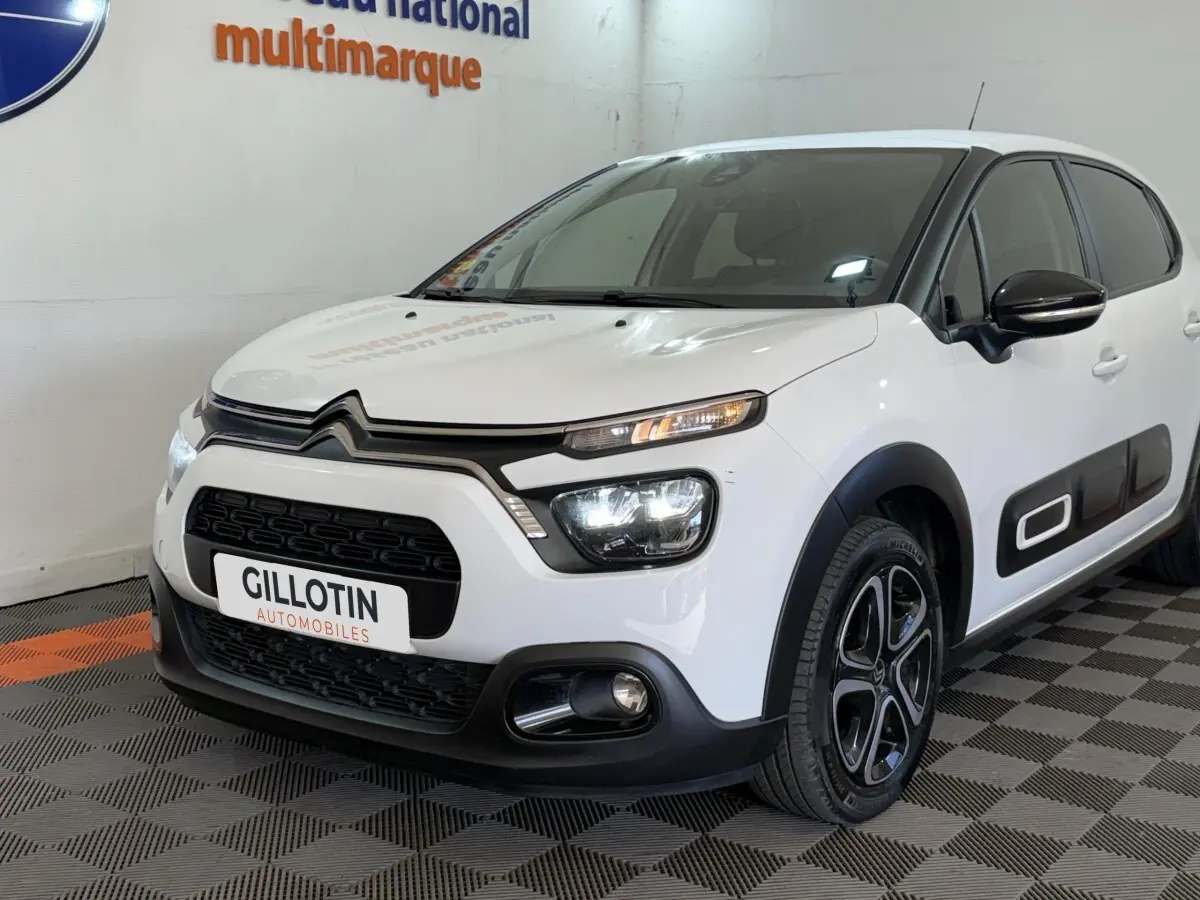 Vue 3/4 avant droite d'une Citroën C3 blanche avec phares LED et protections latérales noires.