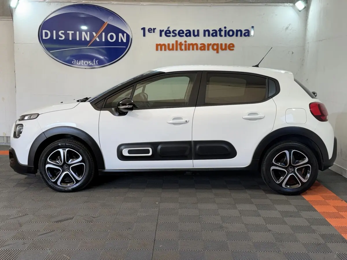 Vue de profil côté gauche d'une Citroën C3 blanche 2021 avec protections noires sur les portières et jantes alliage.